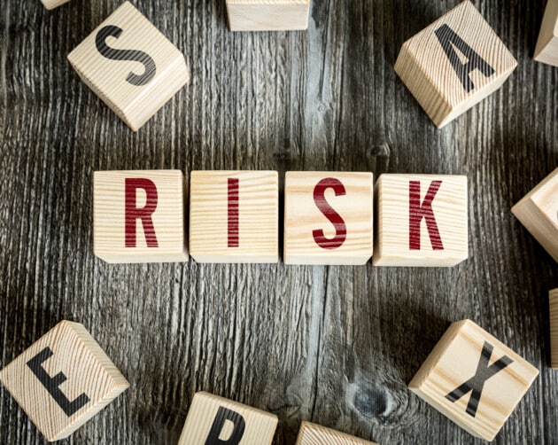 Wooden blocks spelling "RISK" are arranged in the center on a rustic wooden surface, symbolizing risk likelihood. Other scattered blocks with different letters surround them, creating a dynamic composition. ©Mobysoft